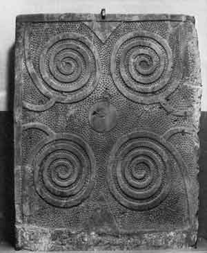 Stone slab carved with curvilinear design against a pitted background